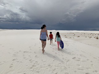 The Ultimate List of Things to Do On an I-10 Road Trip (CA, AZ, NM, TX, LA, AL, MS, FL) 5 Author and her son and daughter walk along the endless, white gypsum sand in White Sands National park. Her daughter is carrying a blue sledding disc.